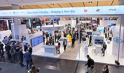 Besucherinnen und Besucher der Hannover Messe stehen am Stand der Plattform Industrie 4.0