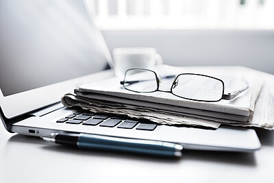 Laptop mit Brille und Zeitung