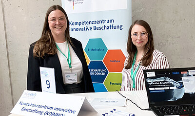 Zwei Frauen stehen am Stand von KOINNO und lächeln in die Kamera.