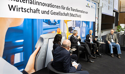 Vier Männer und eine Frau sitzen auf dem Podium und diskutieren.