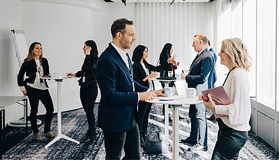 Geschäftsleute stehen an Stehtischen und tauschen sich aus